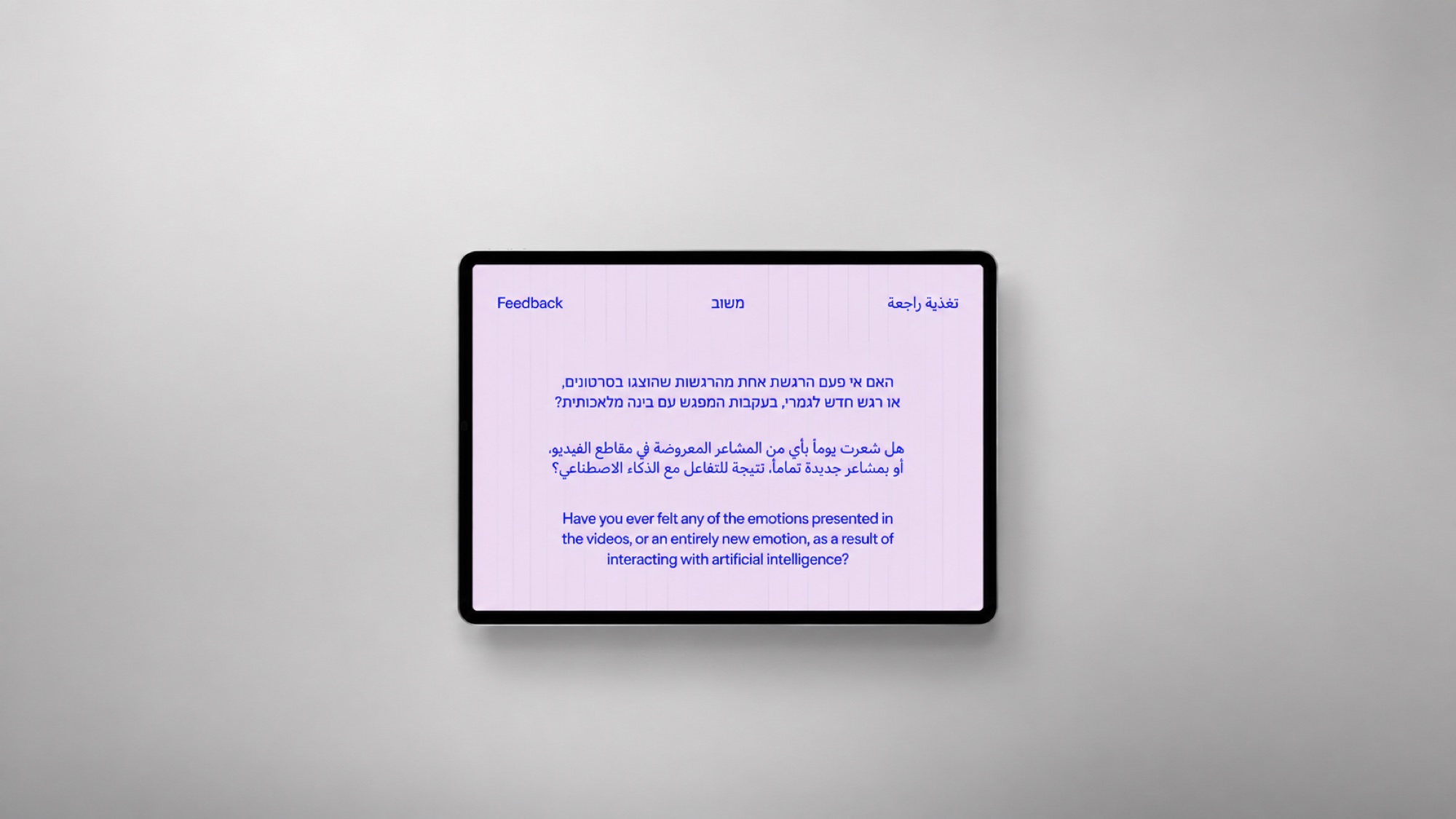 The exhibition's feedback tablet on a grey studio wall: 'Have you ever felt any of the emotions presented in the videos, or an entirely new emotion, as a result of interacting with artificial intelligence?' in English, Hebrew and Arabic