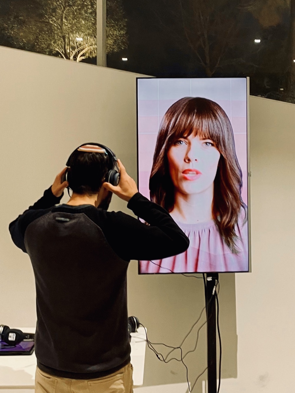 A visitor putting on headphones in front of an instructor's vertical screen