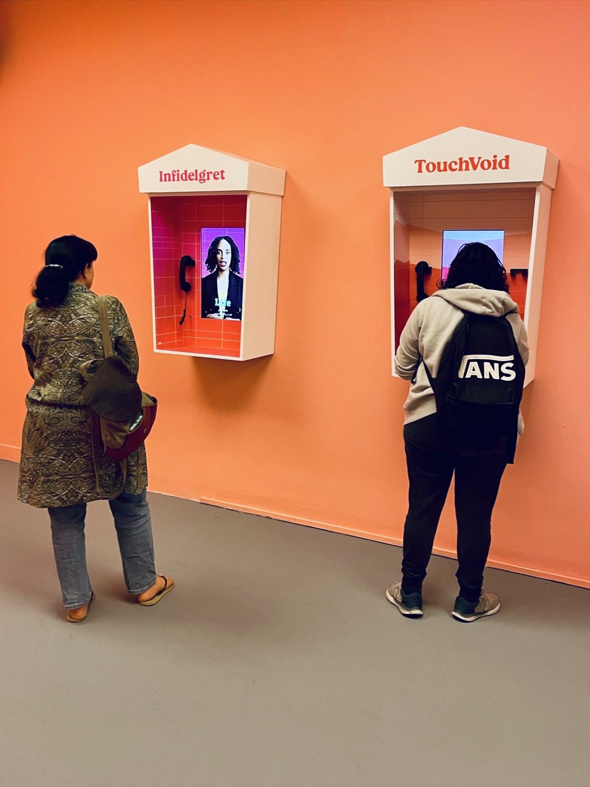 Two visitors listening at the Infidelgret and TouchVoid booths